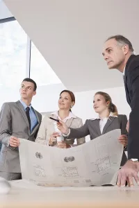 Architect Construction Plan Drucke: Team of four architects discussing an construction plan