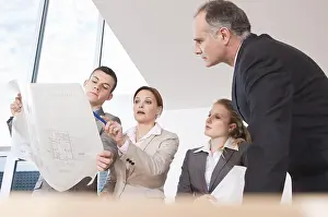 Workplace Collaboration Drucke: Team of four architects discussing an construction plan