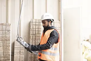 Young Technician Drucke: Technician with beard and helmet works in a workshop
