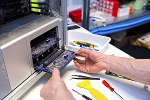 Quality Control Check Drucke: Technician opening the back part of a computer to repair it in a workshop