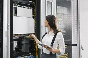 Digital Data Collection Drucke: Technician using tablet pc while analysing server in large data center