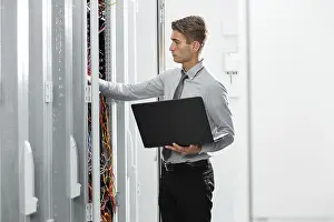 Healthcare Technology Drucke: Technicians using laptop while analyzing server in server room