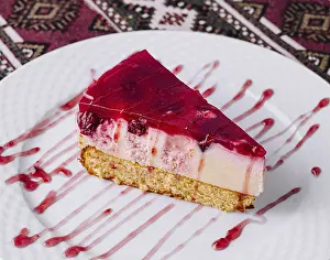 White Tablecloth Drucke: Tempting slice of raspberry cheesecake with syrup on a white plate