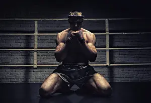 Southeast Asian Sportsman Drucke: Thai boxer prays in the ring. Mongkhon