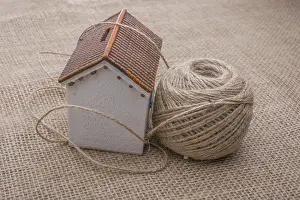 Model House Drucke: Thread wrapped around a model house on a brown background