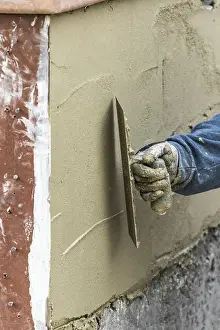 Pool Construction Site Drucke: Tile worker applying cement with trowel at pool construction site