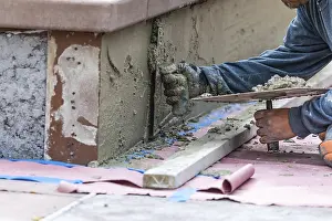 Swimming Pool Installation Drucke: Tile worker applying cement with trowel at pool construction site