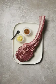 Red Colored Meat Dish Drucke: Top-down view of a raw tomahawk steak presented on a ceramic tray