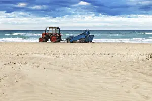Sandy Beach Landscape Drucke: Tractor on the sandy beach cleaning