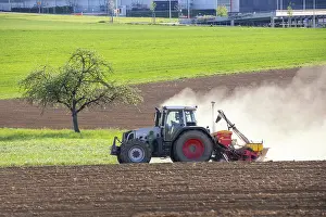 Tractor Seed Drill Drucke: Tractor with seed drill in the field in spring