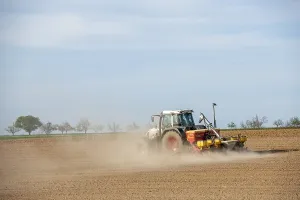 Central European Farmland Drucke: Tractor with seed drill in the field in spring