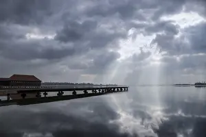 Tranquil Lake Scene Drucke: A tranquil lake scene with a dock and dramatic clouds reflecting on the water's surface