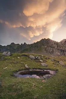Cloudy Sky At Dusk Drucke: A tranquil mountain scene at sunset showcases dramatic