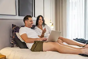 Couple On Bed Drucke: Tranquil scene of a couple lying on the bed using laptop together