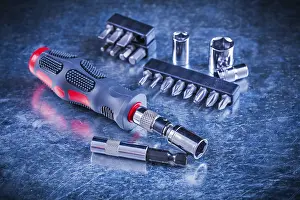Symbolic Construction Image Drucke: Turn screw with set of replaceable bits and torx on scratched metallic background construction concept