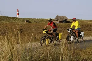 European Lighthouse Photography Drucke: Cyclists in front of the Ostellenbogen Lighthouse