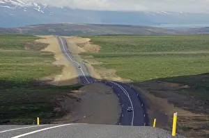 Iceland Travel Photography Drucke: Undulating road without traffic runs into infinity