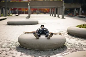 Autumn Foliage Images Drucke: Unrecognizable man lying on a concrete structure