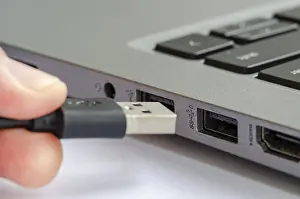 Cybercrime Prevention Tips Drucke: USB being plugged into laptop highlighting risk of unauthorized data transfer or malware