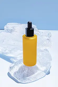 Glass Bottle Cosmetics Drucke: Vibrant yellow serum bottle positioned on a stack of ice