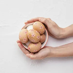 Easter Eggs Drucke: Top view bowl with decorated easter eggs hands