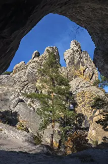 Backlit Rock Formation Drucke: View from a cave onto rocks and a single tree under a blue sky