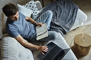 Man Working On Laptop Drucke: Above view of man sitting on sofa and using laptop