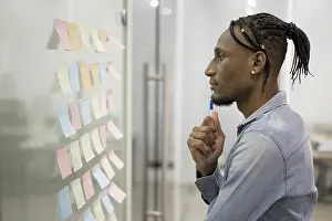 Businessman Thinking Drucke: Side view man thinking office while looking sticky notes