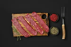 Top View Of Meat Drucke: Top view of raw beef strips on black background