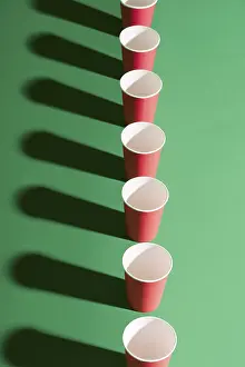 Drucke von Obenansicht von rotem Pappbecher in Reihe auf grünem Hintergrund mit Schatten. Kreatives Konzept, minimalistisch, moderne Kunst Minimalistische Kunstwerke Drucke: Oberansicht von roter Papier-Tasse in Reihe auf grünem Hintergrund mit Schatten.