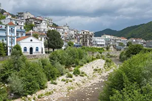 Drucke von Blick auf eine kleine Stadt mit einem Fluss im Vordergrund, umgeben von bewaldeten Bergen und wolkenverhangenem Himmel, Echinos, Zentrum der Pomaken, Myki, Xanthi, Ostmazedonien und Thrakien Fluss Drucke: Ansicht eines kleinen Dorfes mit einem Fluss im Vordergrund.