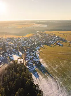 Evening Light In The Black Forest Drucke: View of a wintry village with fields and forests in the sunset light