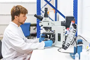 Cancer Research Laboratory Drucke: Side view of a young scientist using microscope to analyse samples in a cancer research laboratory