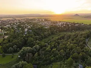 Evening Sun Over Farmland Drucke: A village surrounded by fields and forest at sunset