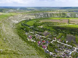Drucke von Ein Dorf, das von Hügeln und Bäumen umgeben ist, mit einem angrenzenden Flusslauf und landwirtschaftlichem Land, Luftbild, Schleife des Răut, Raut, Blick auf Trebujeni, Alt-Orhei, Orheiul Vechi Moldawien Drucke: Ein Dorf umgeben von Hügeln und Bäumen.