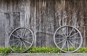 North Rhine Westphalia Europe Drucke: Two wagon wheels lean against a barn wall