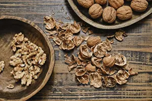 Walnut Shells Drucke: Whole walnuts and broken shells scattered across a wooden table