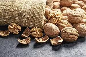 Deserted Table Scene Drucke: Walnuts are spilled out of the bag onto a black table