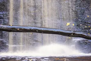 Uninhabited River Scenery Drucke: Waterfall on a rock face with a tree log