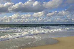Cumulus Humilis Clouds Drucke: Waves running out at the sandy beach