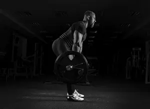 Fitness Studio Workout Drucke: The weightlifter performs an exercise called deadlift