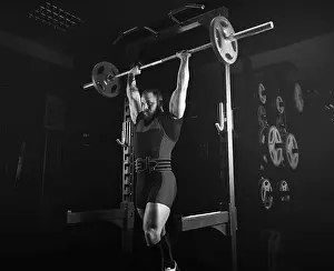 Fitness Training Drucke: The weightlifter raises the barbell above his head and fixes the weight