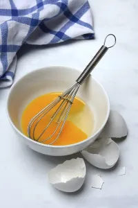 Plain Colored Background Eggs Drucke: Whipped egg in shell with whisk, egg shells