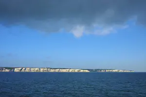 Chalk Cliff Coastline Drucke: White cliffs under a dramatic sky with cloud formations over blue water
