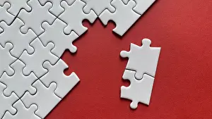 Plain Colored Background Image Drucke: White puzzle with two separate pieces missing on a red background