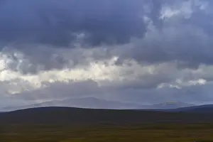 European Hilly Landscapes Drucke: Wide hilly landscape under dramatic cloudy sky with subdued light