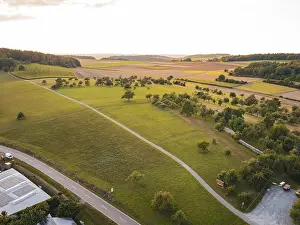 Sunset Travel Photography Drucke: Wide landscape with fields and trees in the soft light of sunset