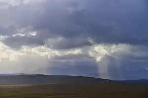 Cloudy Sky Landscapes Europe Drucke: Wide landscape with rolling hills and rays of light falling through clouds