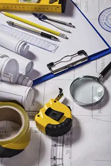 Deserted Construction Site Image Drucke: Wiew on a typical engineer workplace with blueprint and measuring tools vertical