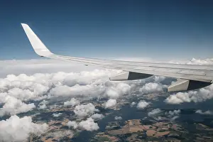Aviation Industry Images Drucke: Wing of an airplane flying above the clouds